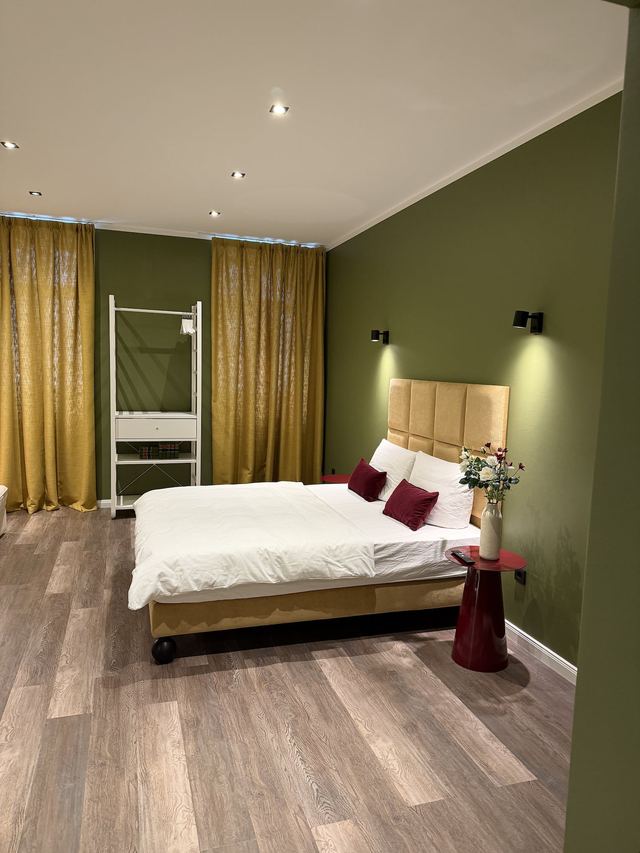 Bedroom with double bed and golden curtains in the Prestige Suites, Berlin